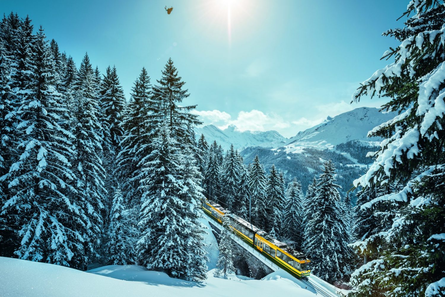 Treinreizen Zwitserland winter-trein van de Jungfraubahn in de sneeuw bij Wengen en paragliden